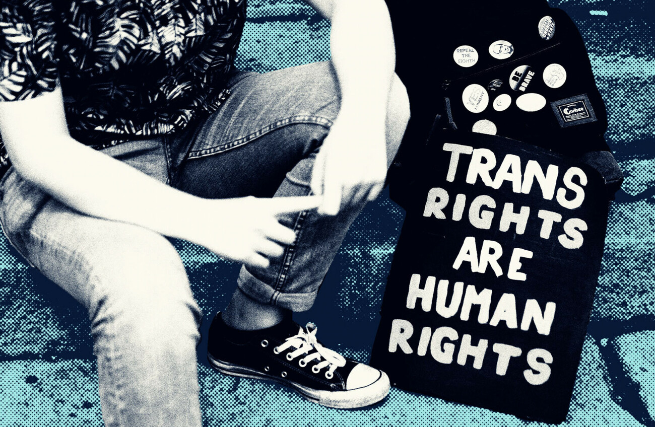 A person sits with a sign that says "Trans rights are human rights"